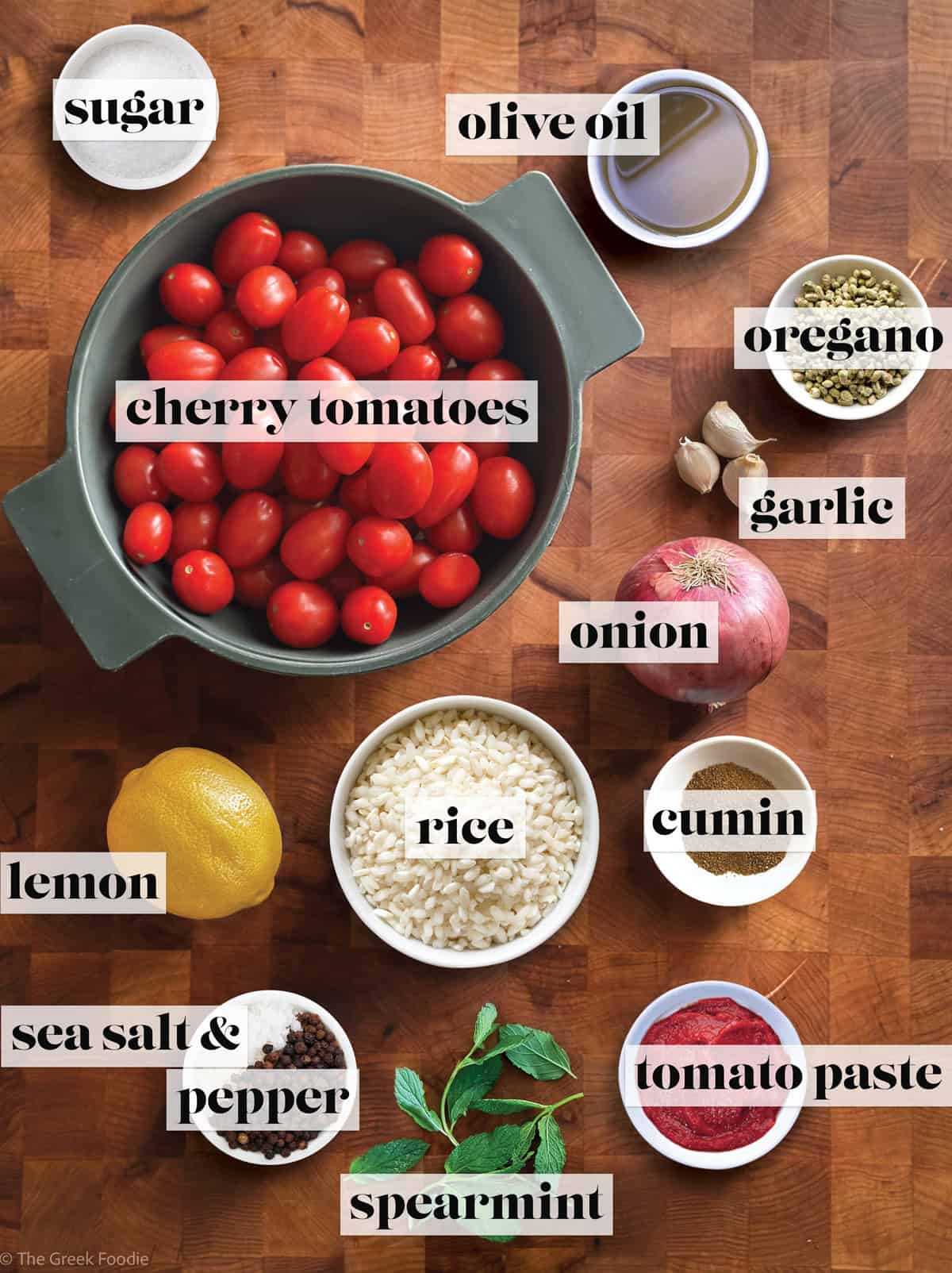 Ingredients to make Greek tomato rice on a wooden surface.