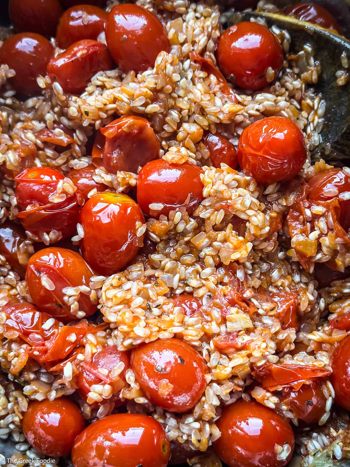 Cherry tomatoes with ricen cooking and a wooden fork.