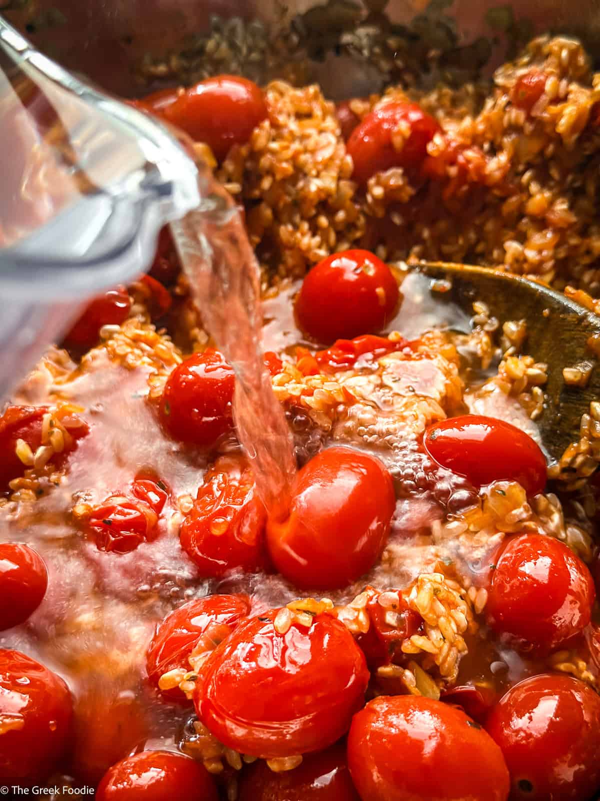 Water pouring into tomatoes and rice cooking.