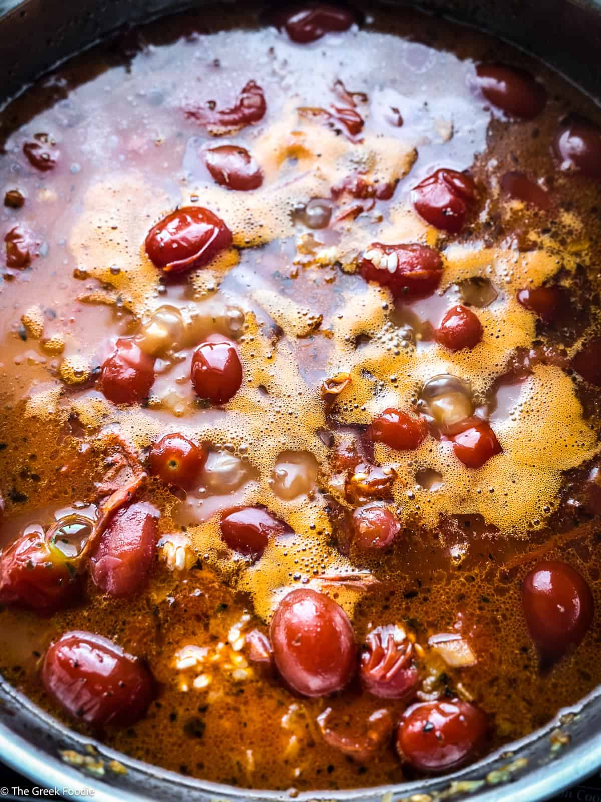 Cherry tomatoes with rice and broth cooking.