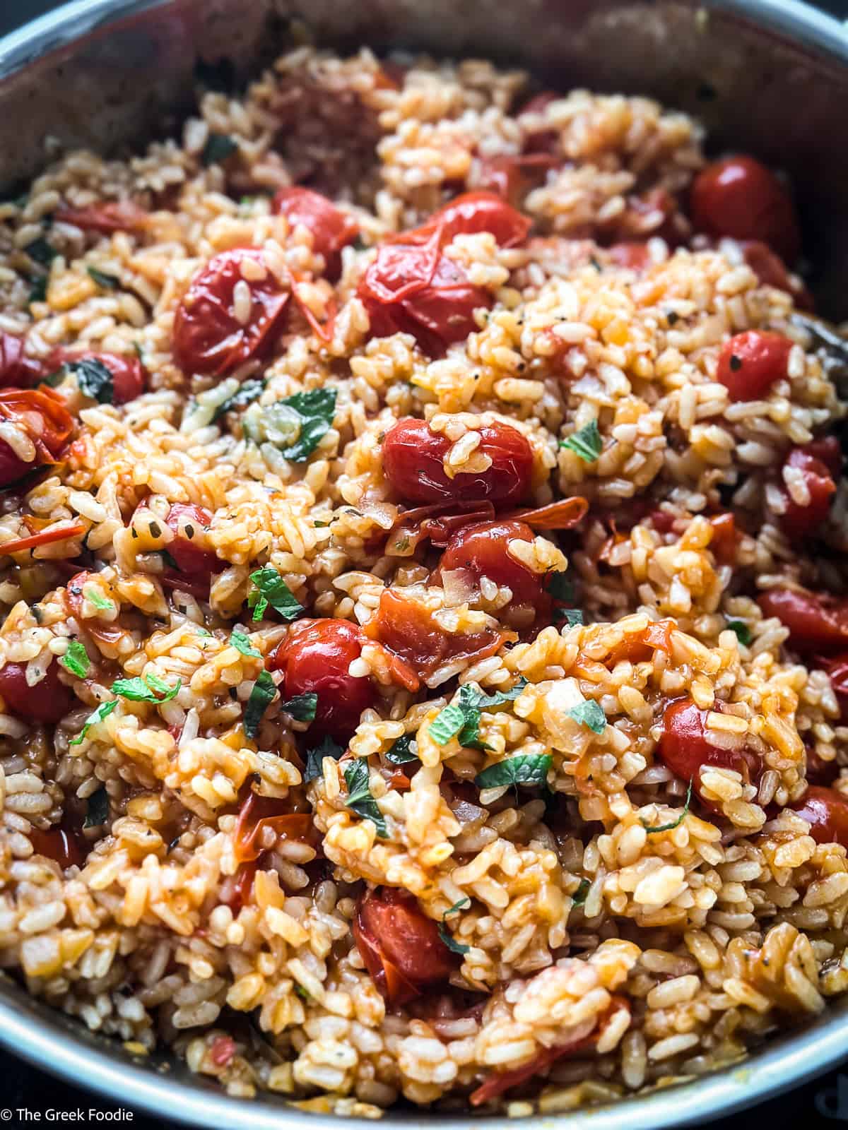 Tomato rice-ntomatorizo, and herbs in a saucepan.