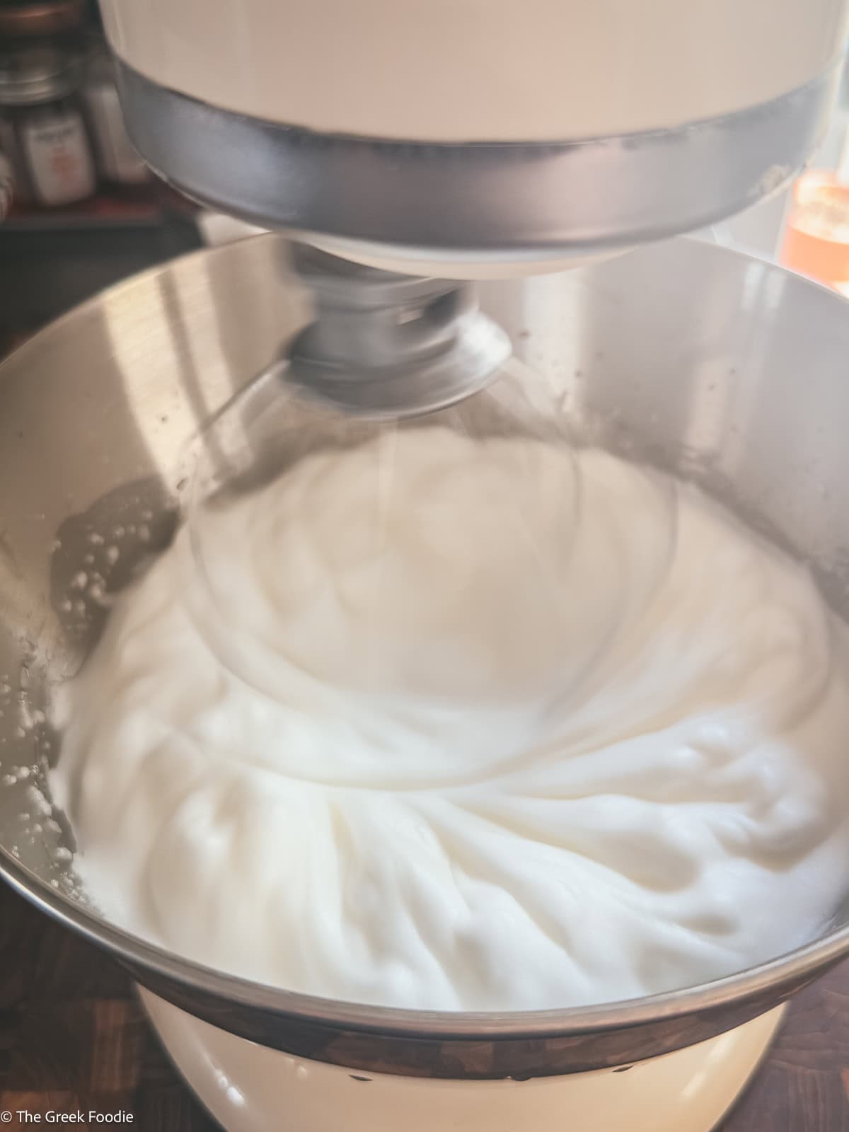 A whisk beating egg whites in a mixer.