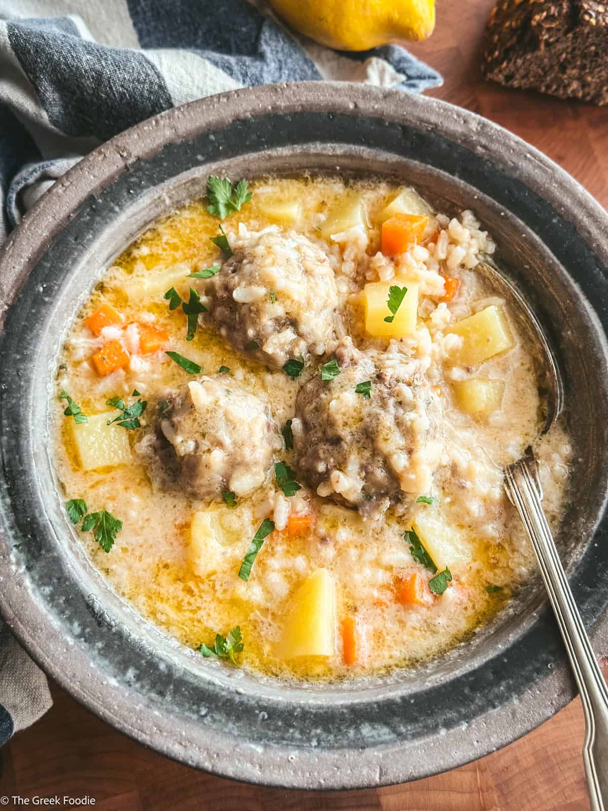 Youvarlakia meatballs with rice, broth in a plate with a spoon.