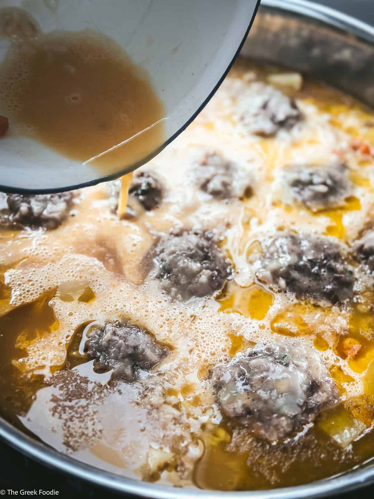 Avgolemono is poured into youvarlakia soup.
