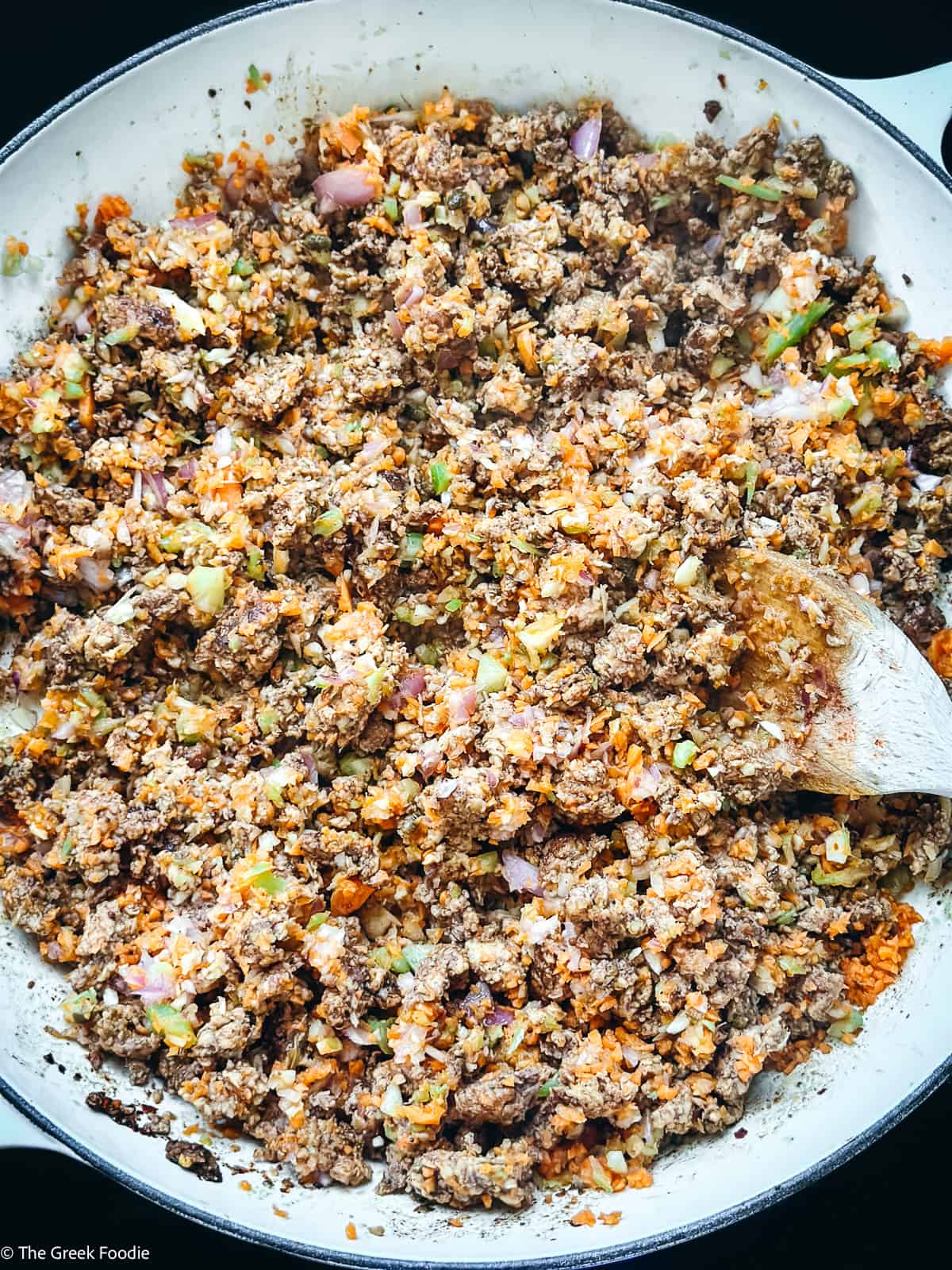 Ground chicken and diced veggies in a pot cooking with a sprig of thyme.