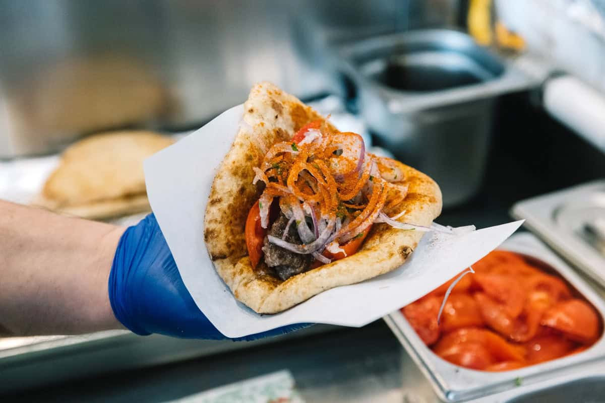 A hand holding a souvlaki with pita.