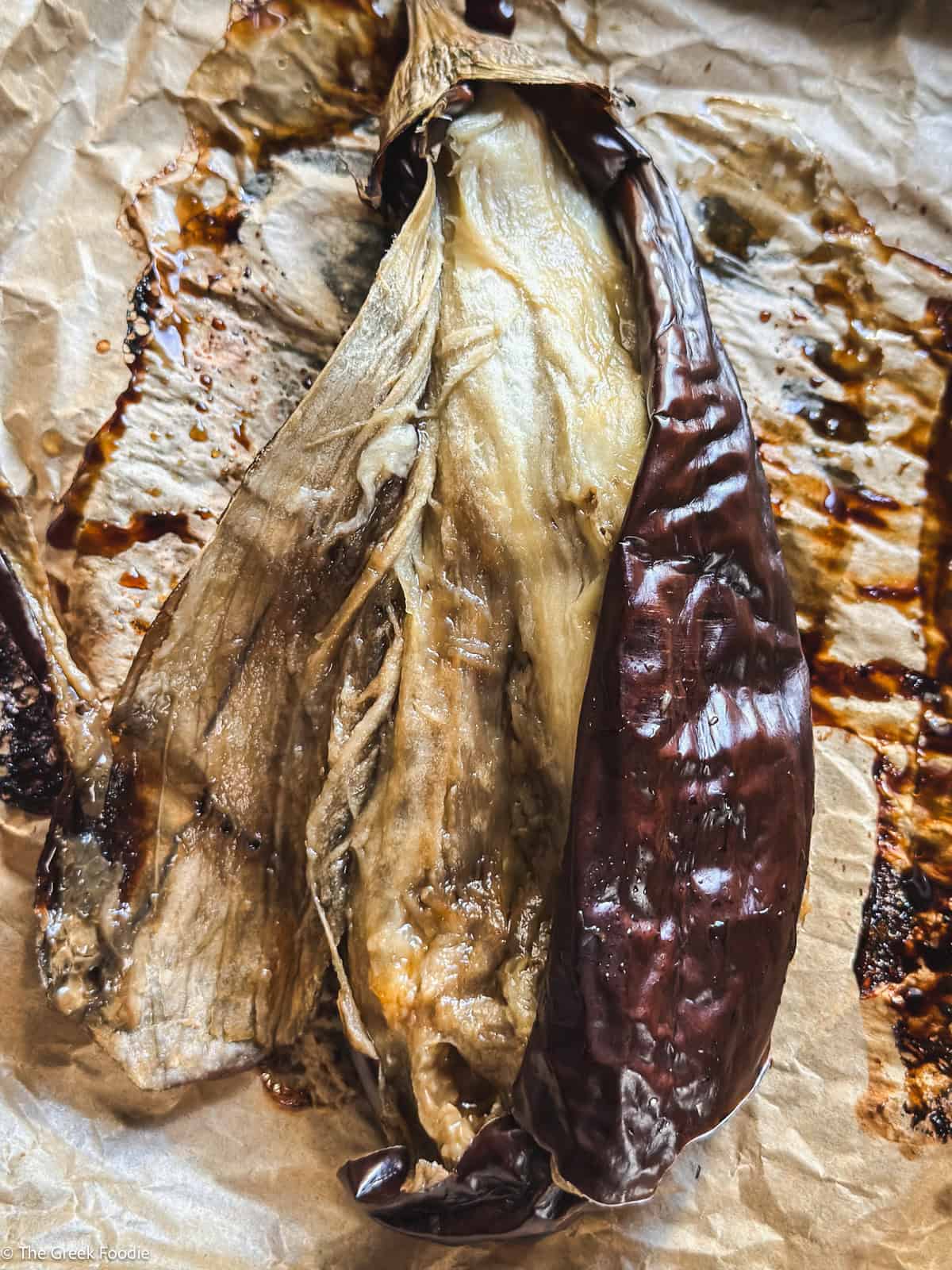 A baked eggplant cut in half with the flesh exposed.