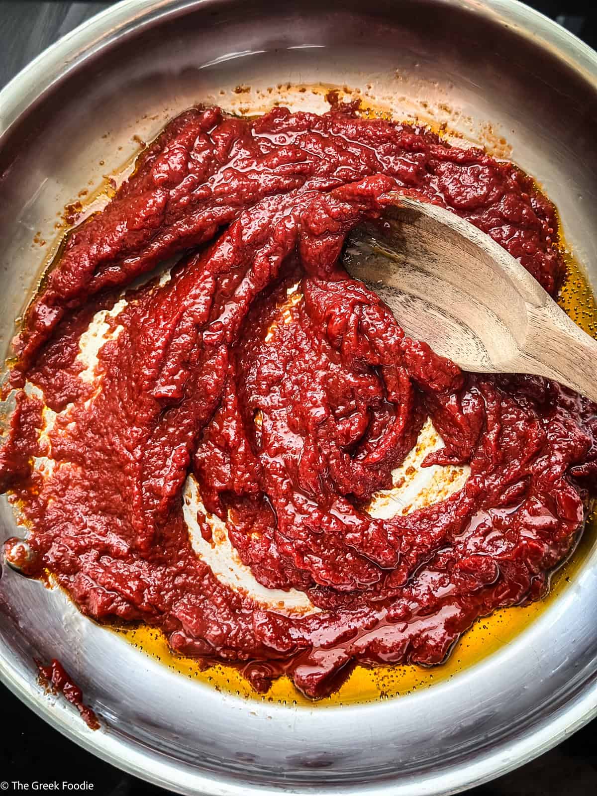 Tomato paste cooking in olive oil in a pan for Greek melitzanosalata tomato sauce.