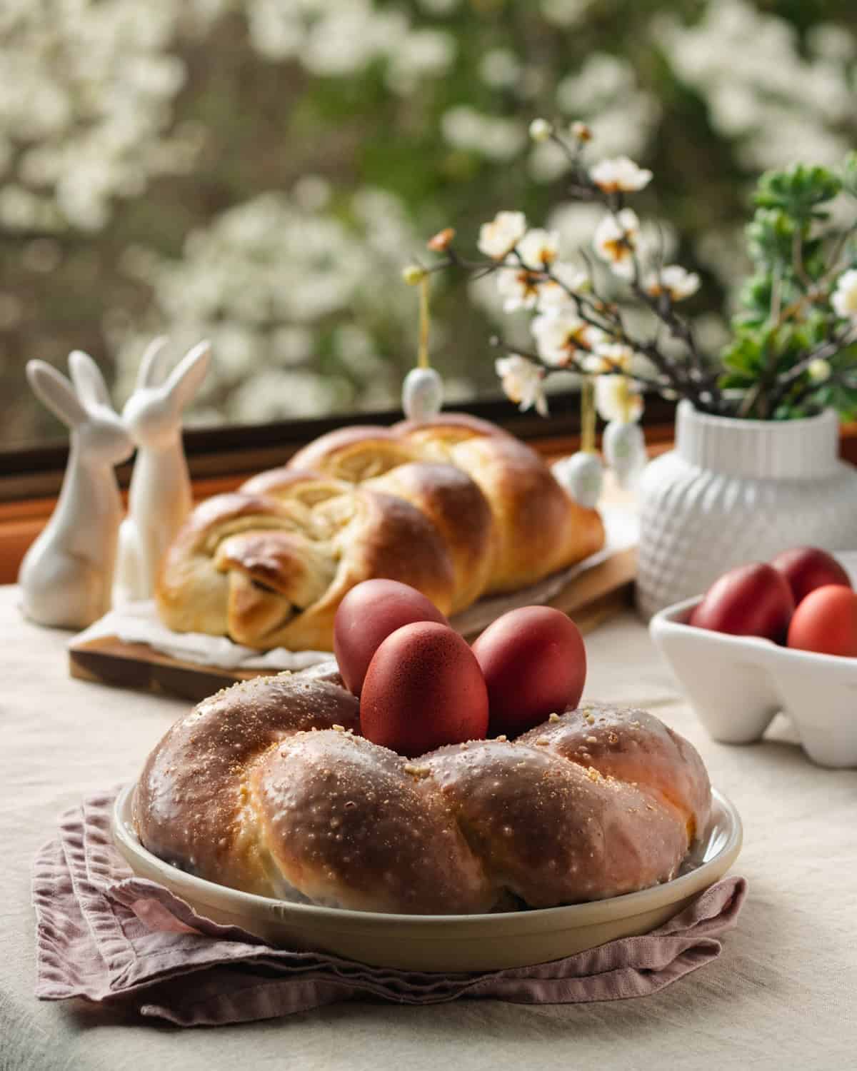 A table setting with Greek tsoureki bread and red eggs for Easter.