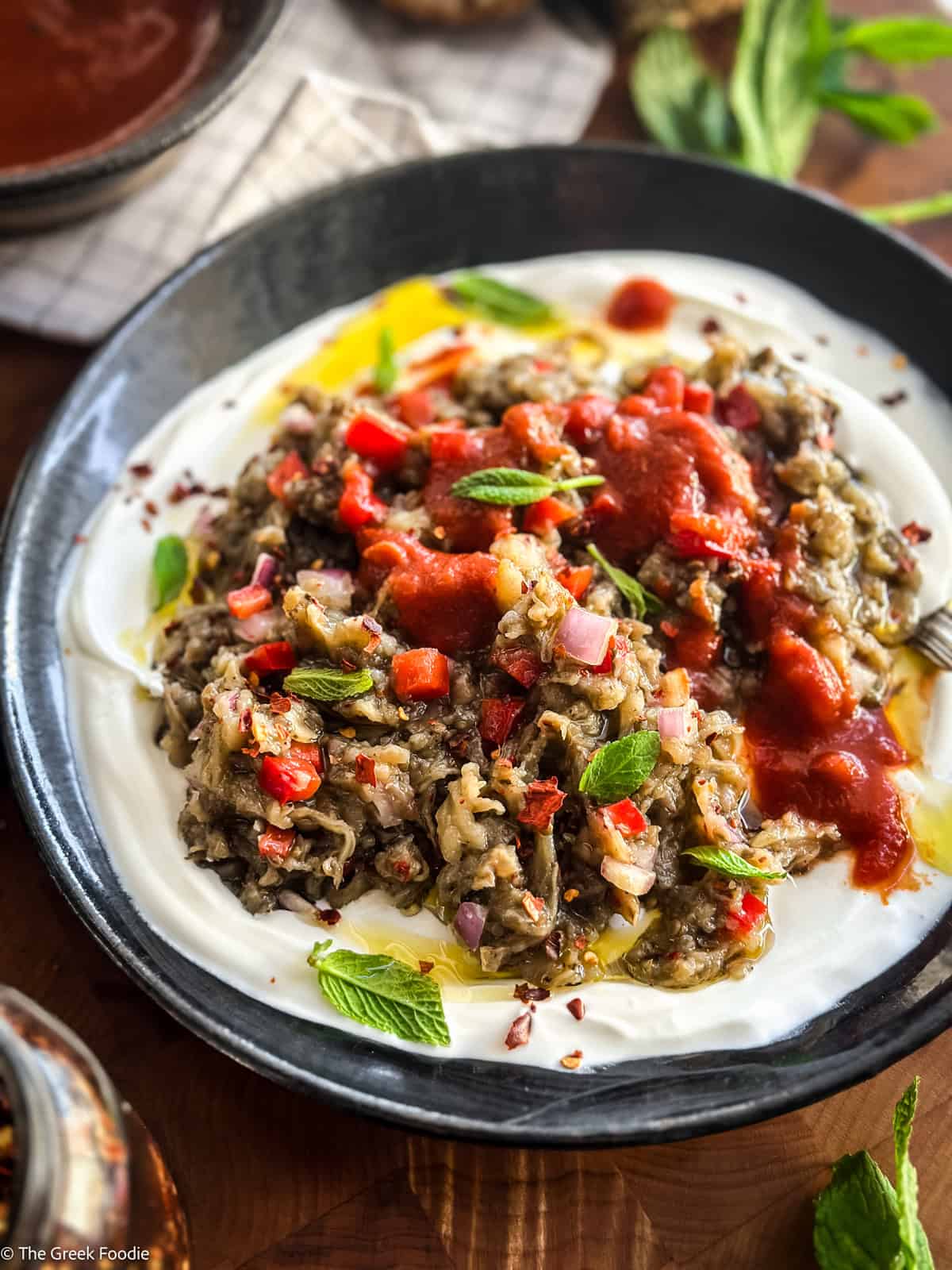 Greek melitzanosalata served over strained yogurt and topped with tomato sauce.