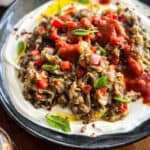 Greek melitzanosalata served over strained yogurt and topped with tomato sauce.