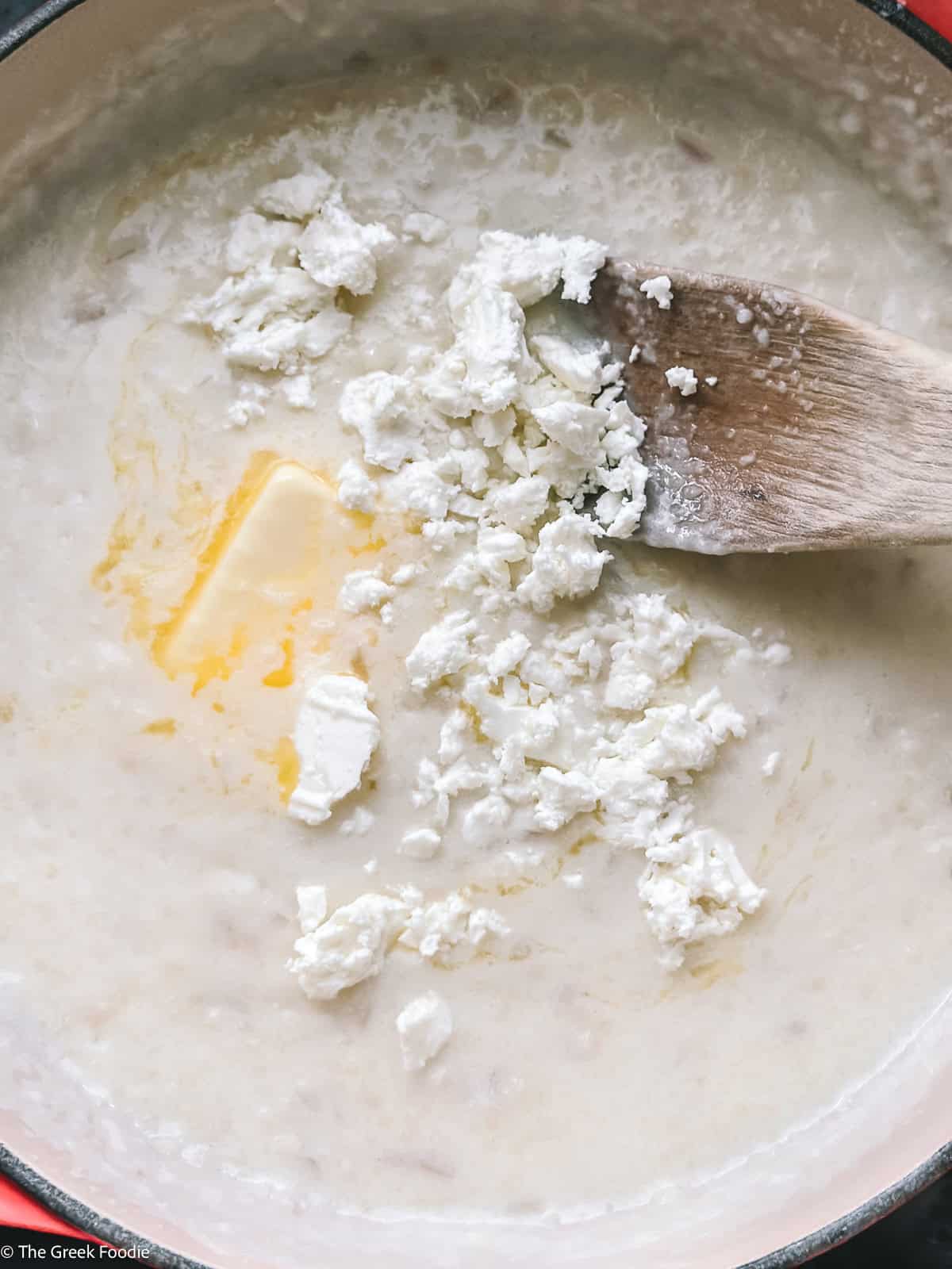 Butter and crumbled feta melting into creamy Greek trahanas soup at the end of cooking.