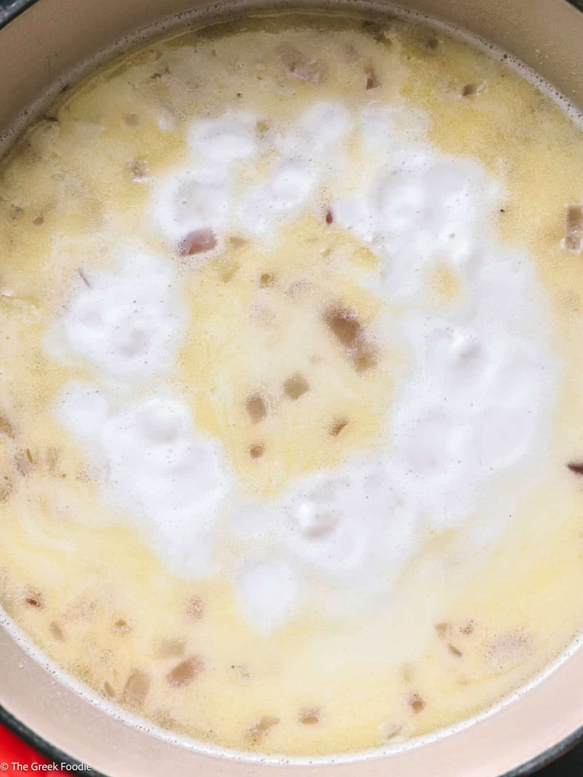 Greek trahanas soup simmering with milk and water until creamy and thickened.