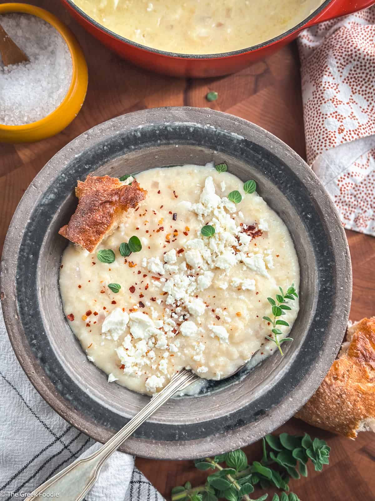 Close-up of creamy Greek trahanas soup with feta cheese, black pepper, oregano, and olive oil, a classic Greek comfort food.