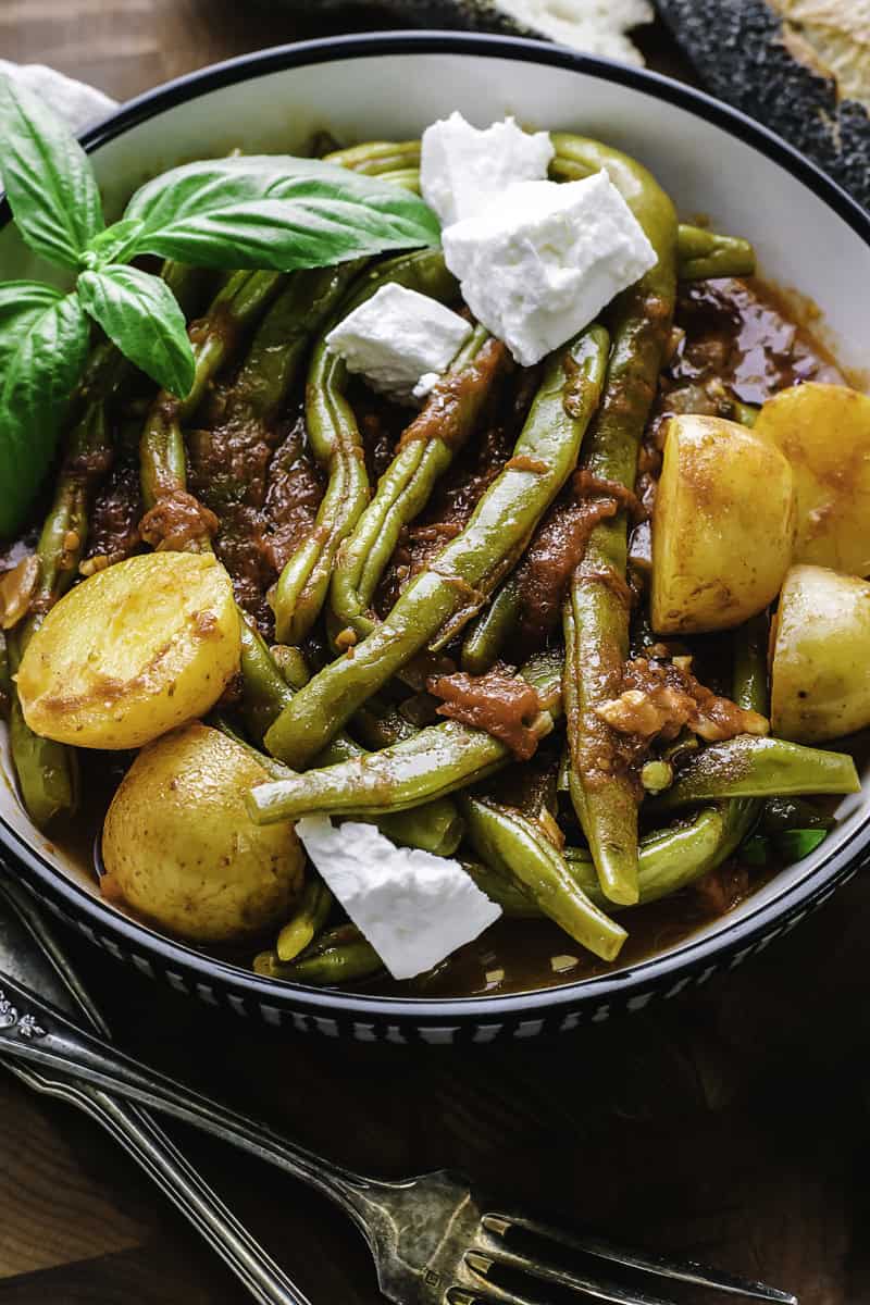 A plate with Greek fasolakia-green beans in a tomato sauce with feta.