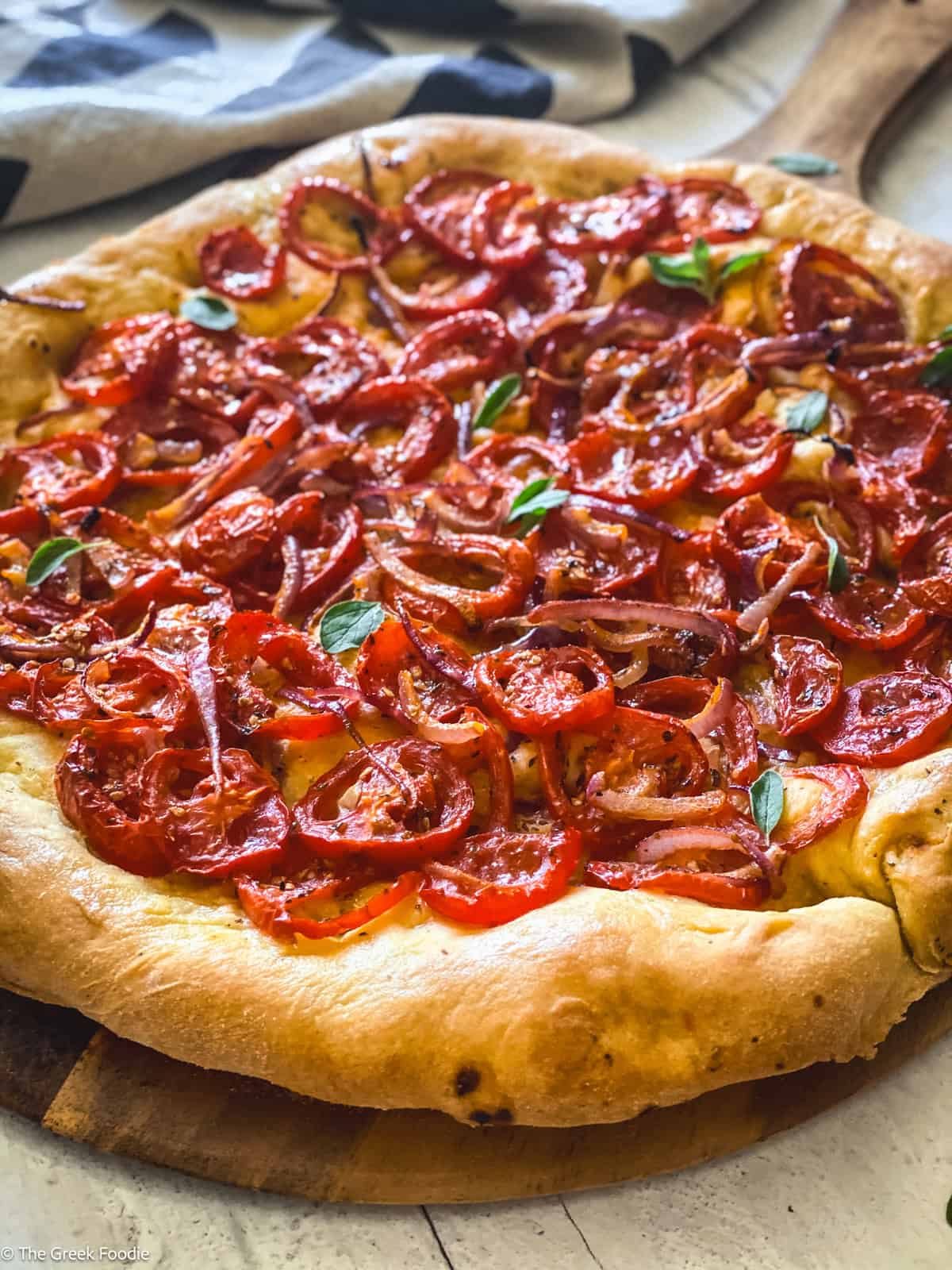 Ladenia is a traditional Greek tomato flatbread topped with juicy tomatoes, onions, and olive oil.