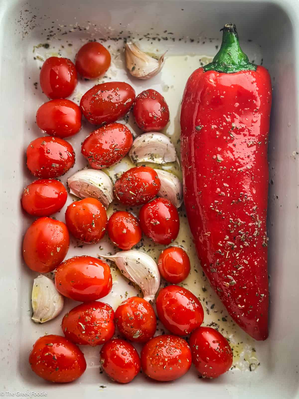 Cherry tomatoes, whole garlic cloves, and longhorn red pepper seasoned with olive oil and oregano before roasting.