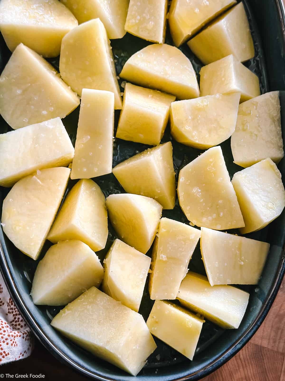 Raw Yukon Gold potatoes cut into large chunks and arranged on a sheet pan with olive oil and sea salt before roasting.