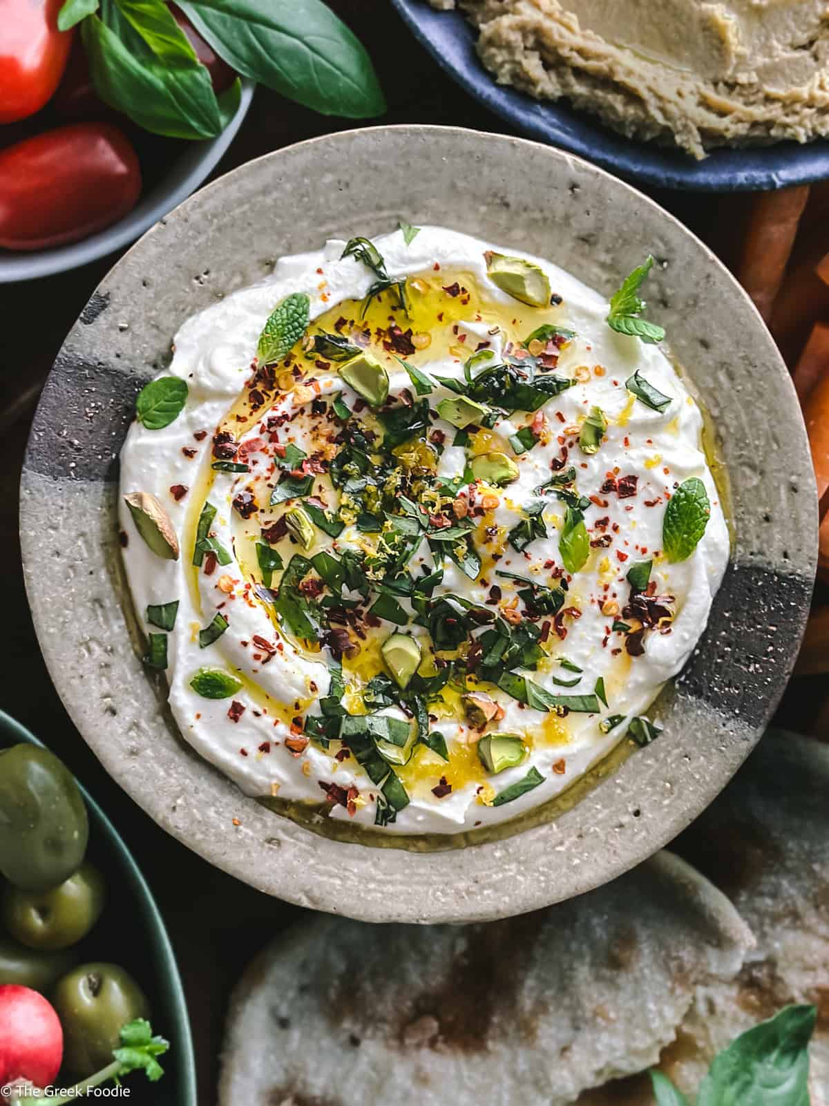 Greek whipped feta dip served with pita bread, olives, carrots, and hummus on a mezze platter.