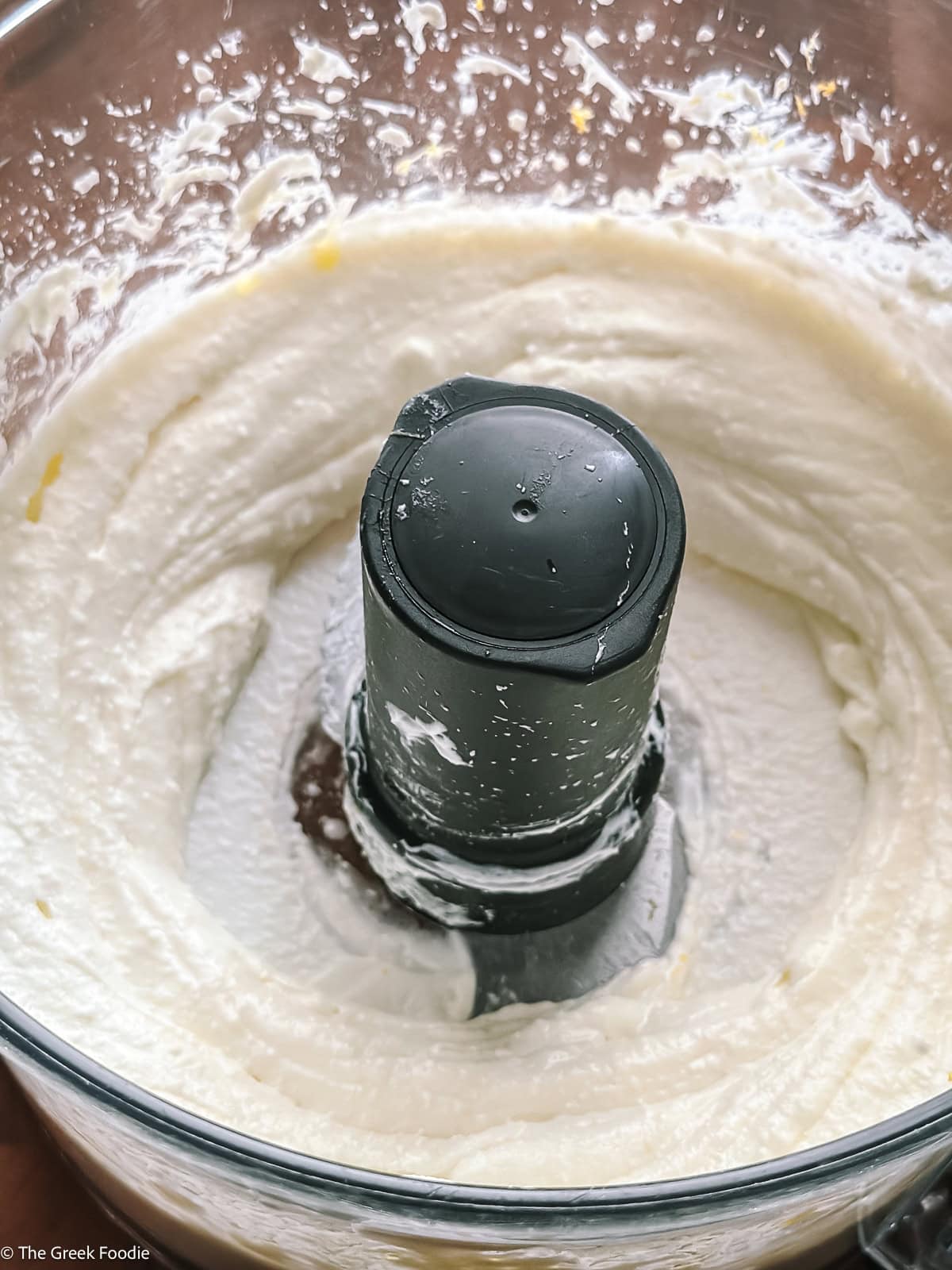 Creamy whipped yogurt feta dip blended smooth in a food processor bowl.
