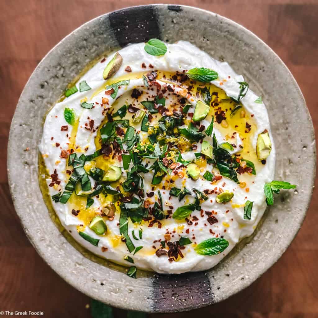 Whipped yogurt feta dip topped with olive oil, fresh herbs, lemon zest, red pepper flakes, and pistachios.