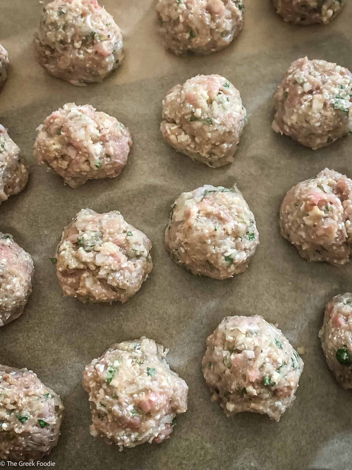 Uncooked low-carb turkey meatballs shaped and ready for cooking on a parchment-lined baking sheet.