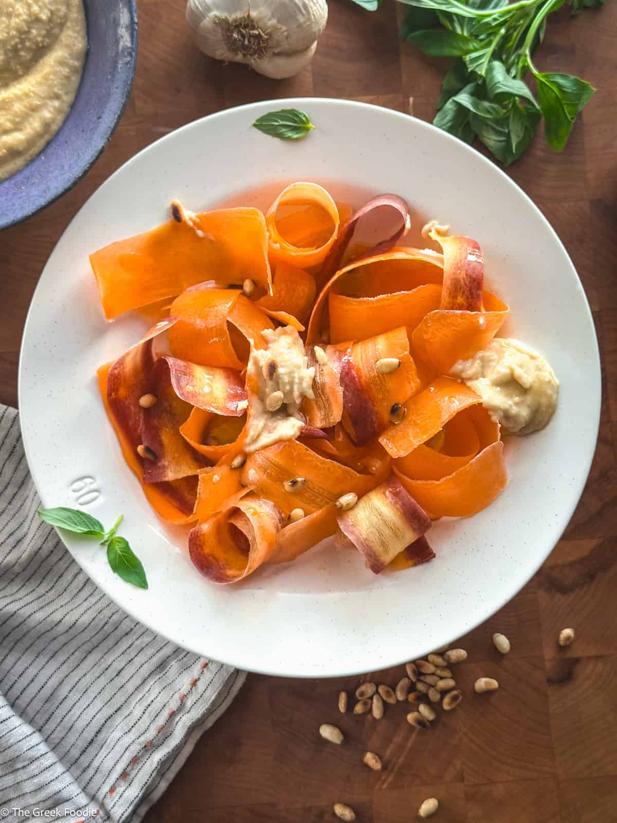 Greek-style carrot ribbon salad with almond skordalia, toasted pine nuts, and a drizzle of olive oil.