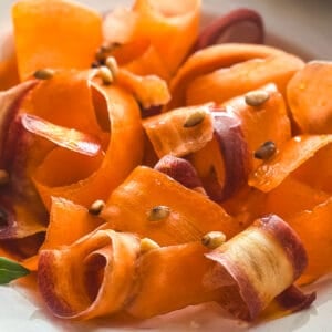 Close-up of carrot ribbons tossed in oxymelo honey-vinegar dressing with almond skordalia.
