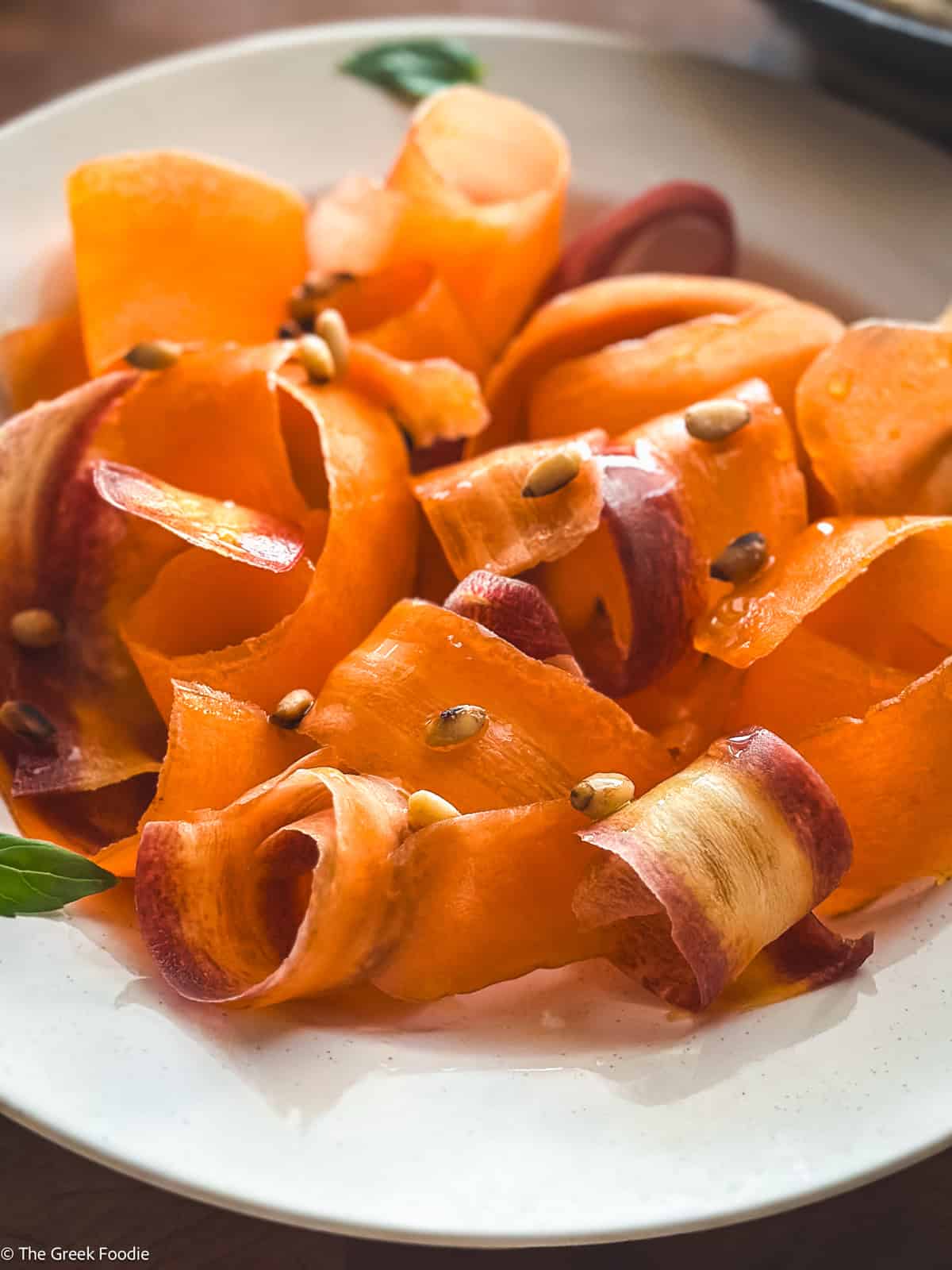 Close-up of carrot ribbons tossed in oxymelo honey-vinegar dressing with almond skordalia.
