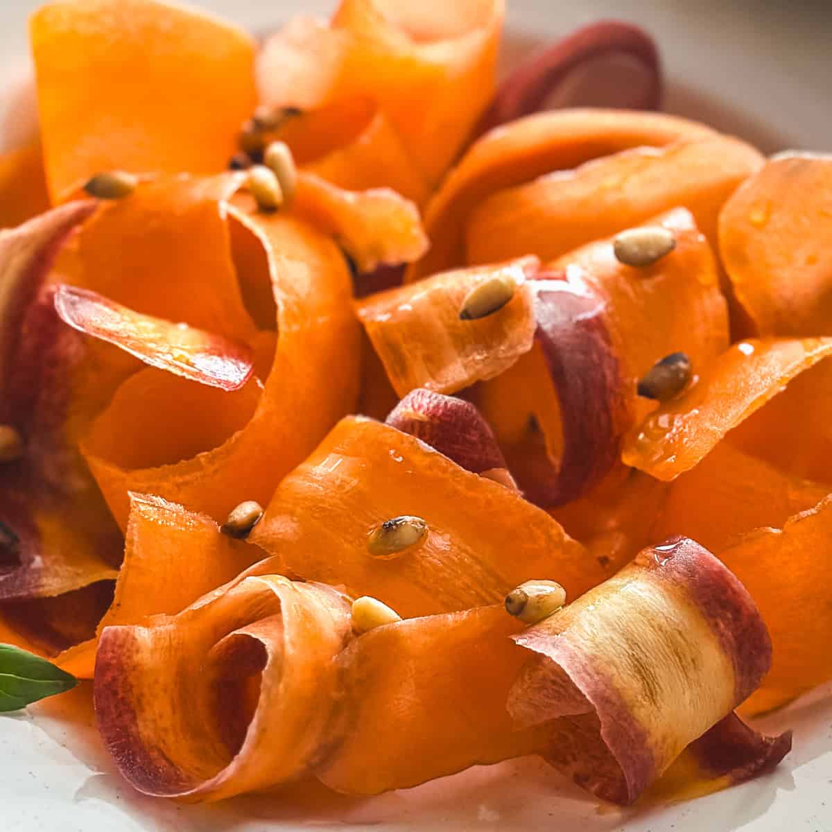 Close-up of carrot ribbons tossed in oxymelo honey-vinegar dressing with almond skordalia.