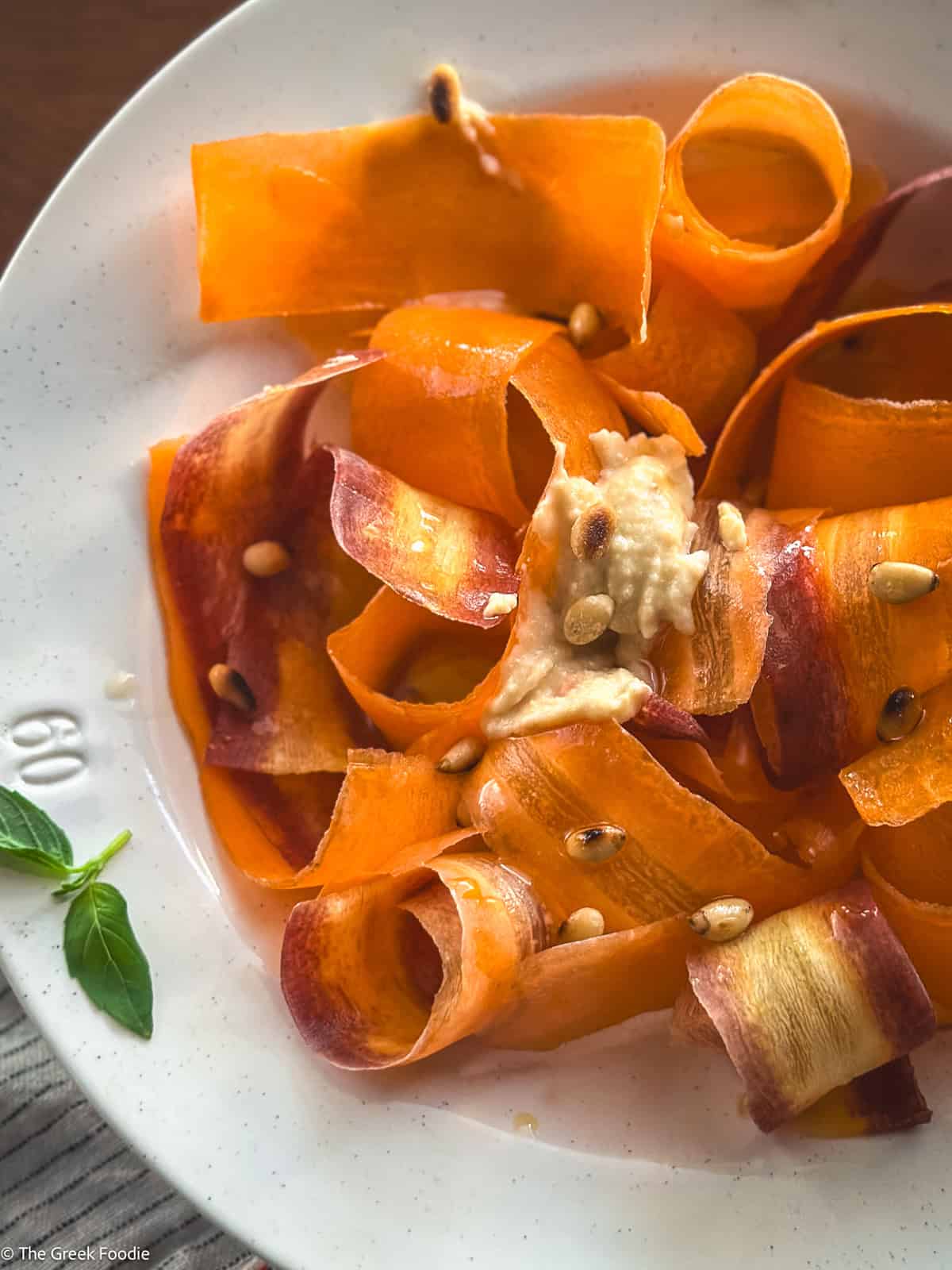 Close-up of carrot ribbons tossed in oxymelo honey-vinegar dressing with almond skordalia.