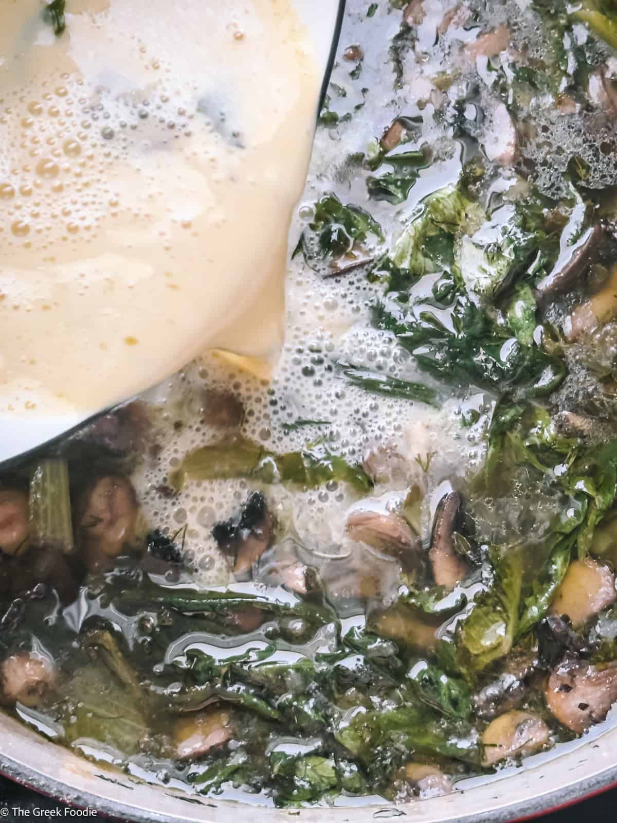 Pouring tempered avgolemono into mushroom magiritsa Greek Easter soup