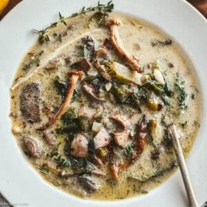 Greek mushroom magiritsa soup in a white bowl with red Easter egg and lemon
