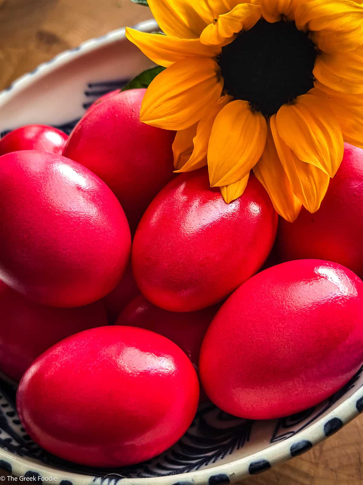 Greek red Easter eggs in a blue and white bowl with a sunflower