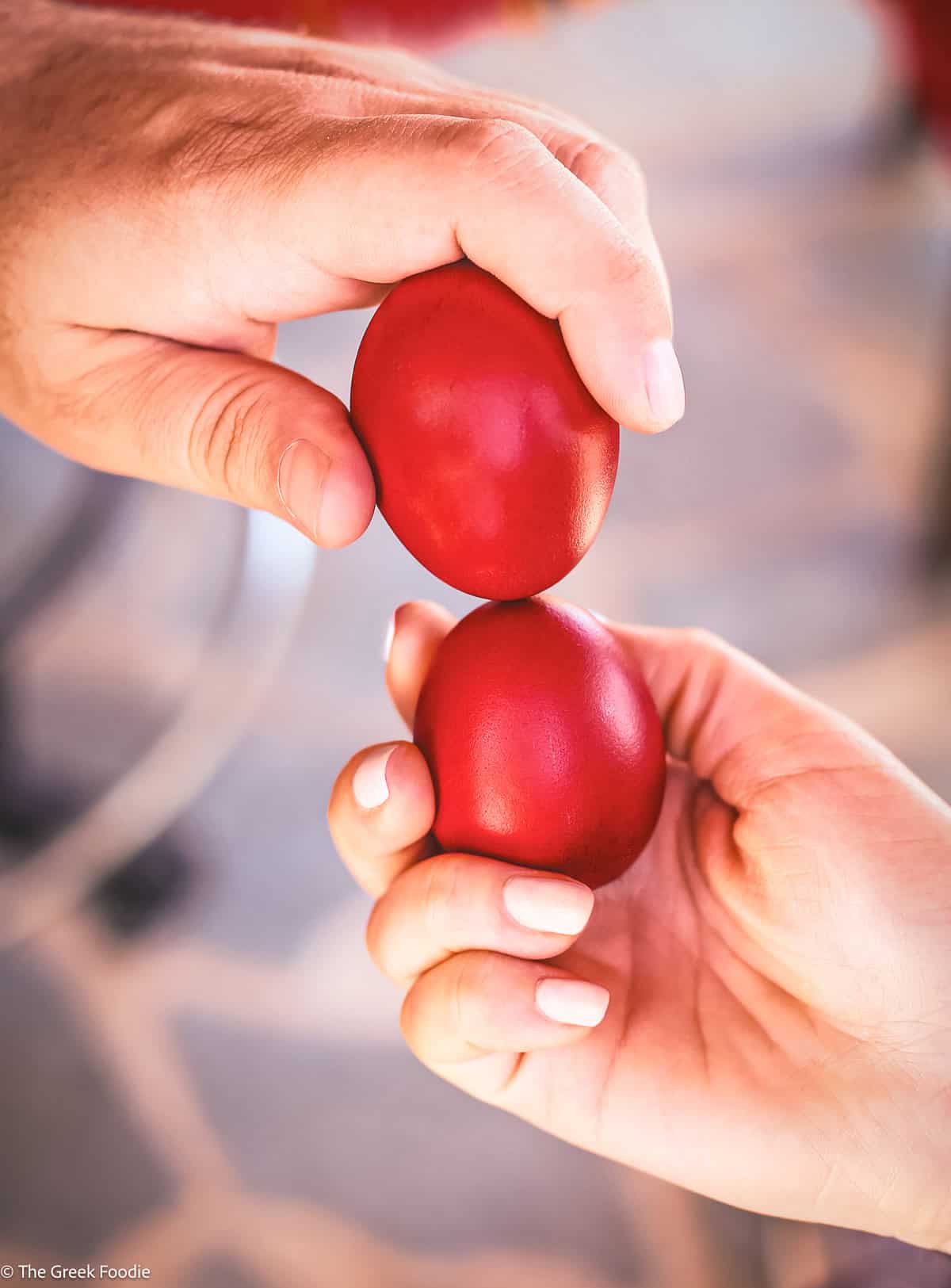 Two hands cracking Greek red Easter eggs — the tsougrisma tradition