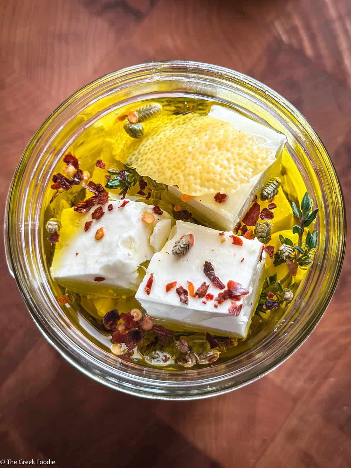 Marinated feta cubes in a glass jar with olive oil, garlic, and fresh thyme