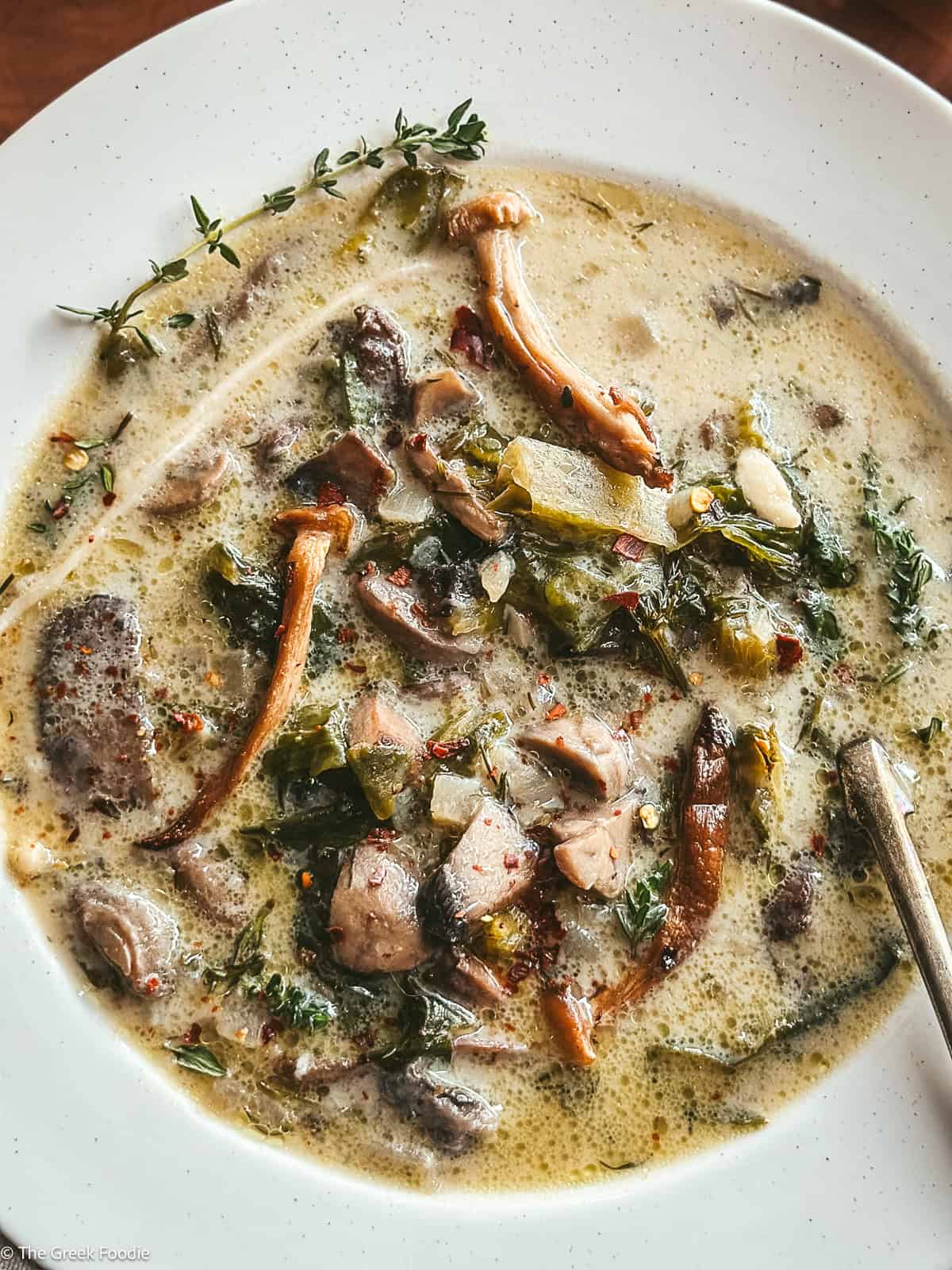 Greek mushroom magiritsa soup in a white bowl with red Easter eggs and lemon