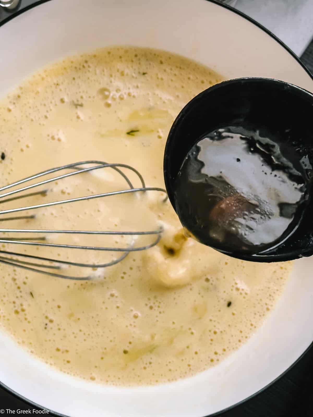 Whisking egg lemon avgolemono with hot broth for Greek mushroom magiritsa