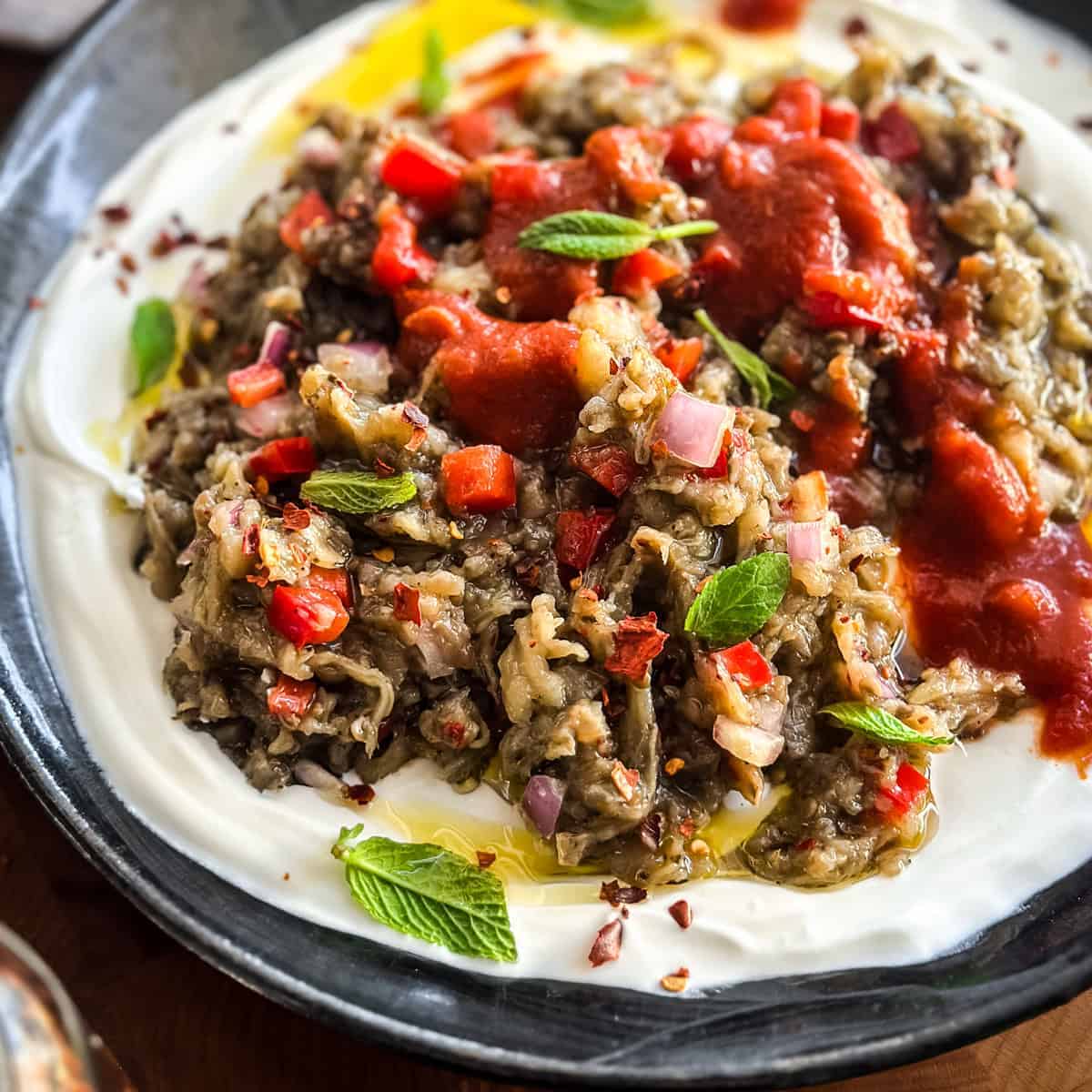 Greek melitzanosalata served over strained yogurt and topped with tomato sauce