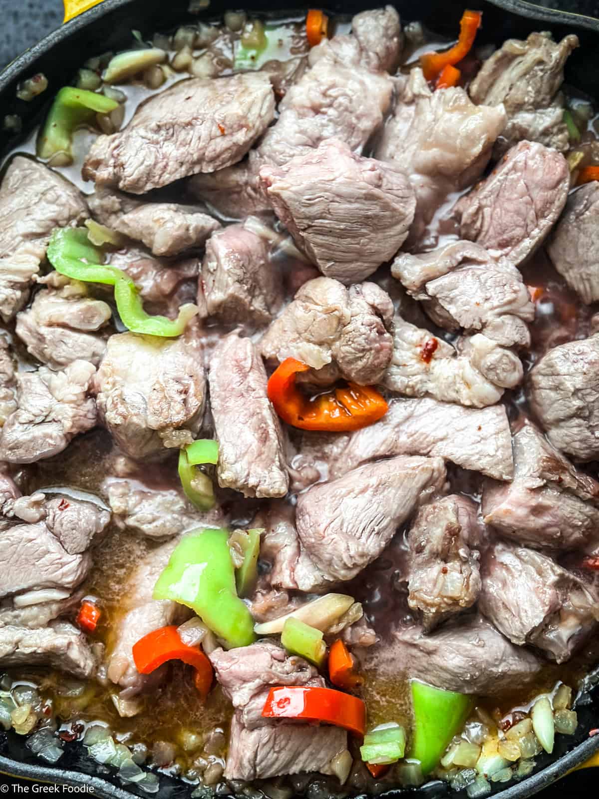 Seared pork neck returned to the pan with softened peppers and onions, deglazing with red wine for bekri meze
