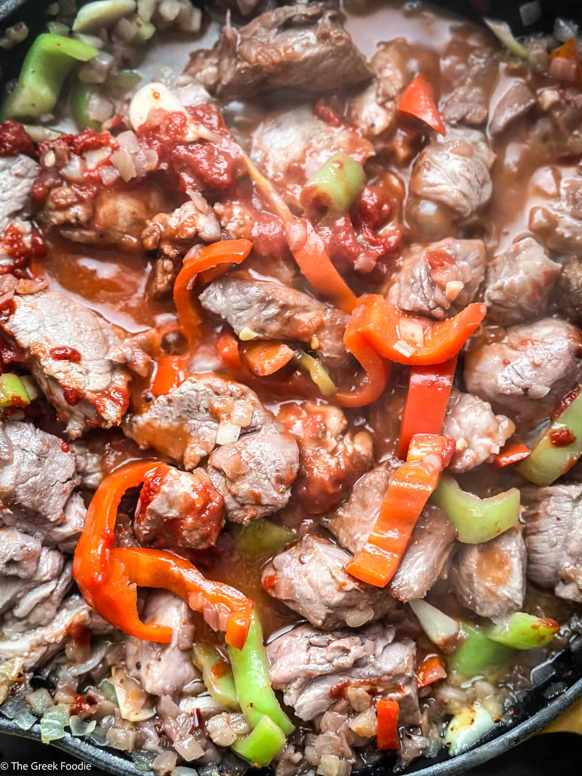 bekri-meze-tomato-paste.jpg Tomato paste stirred into pork and peppers in a cast iron pan — building the sauce for Greek bekri meze