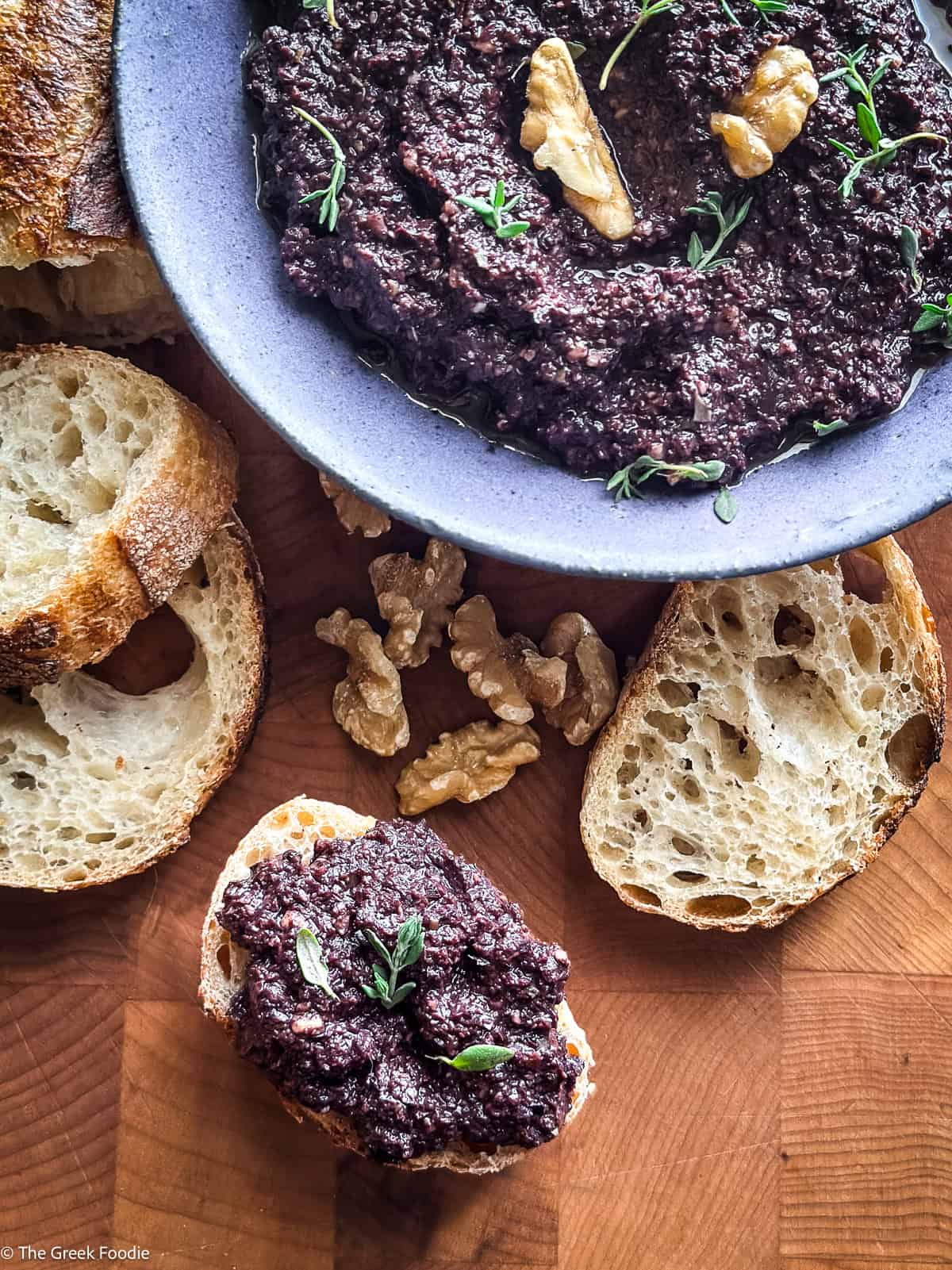 Beautiful photos! Here's the alt text for each image: greek-kalamata-olive-tapenade-bread.jpg Kalamata olive tapenade in a grey bowl surrounded by toasted bread slices and walnuts on a wooden board