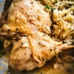 Two pieces of kotópoulo lemonáto — chicken thigh and drumstick — resting on pilafi rice with golden lemon sauce