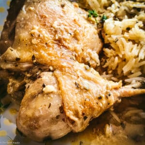 Two pieces of kotópoulo lemonáto — chicken thigh and drumstick — resting on pilafi rice with golden lemon sauce