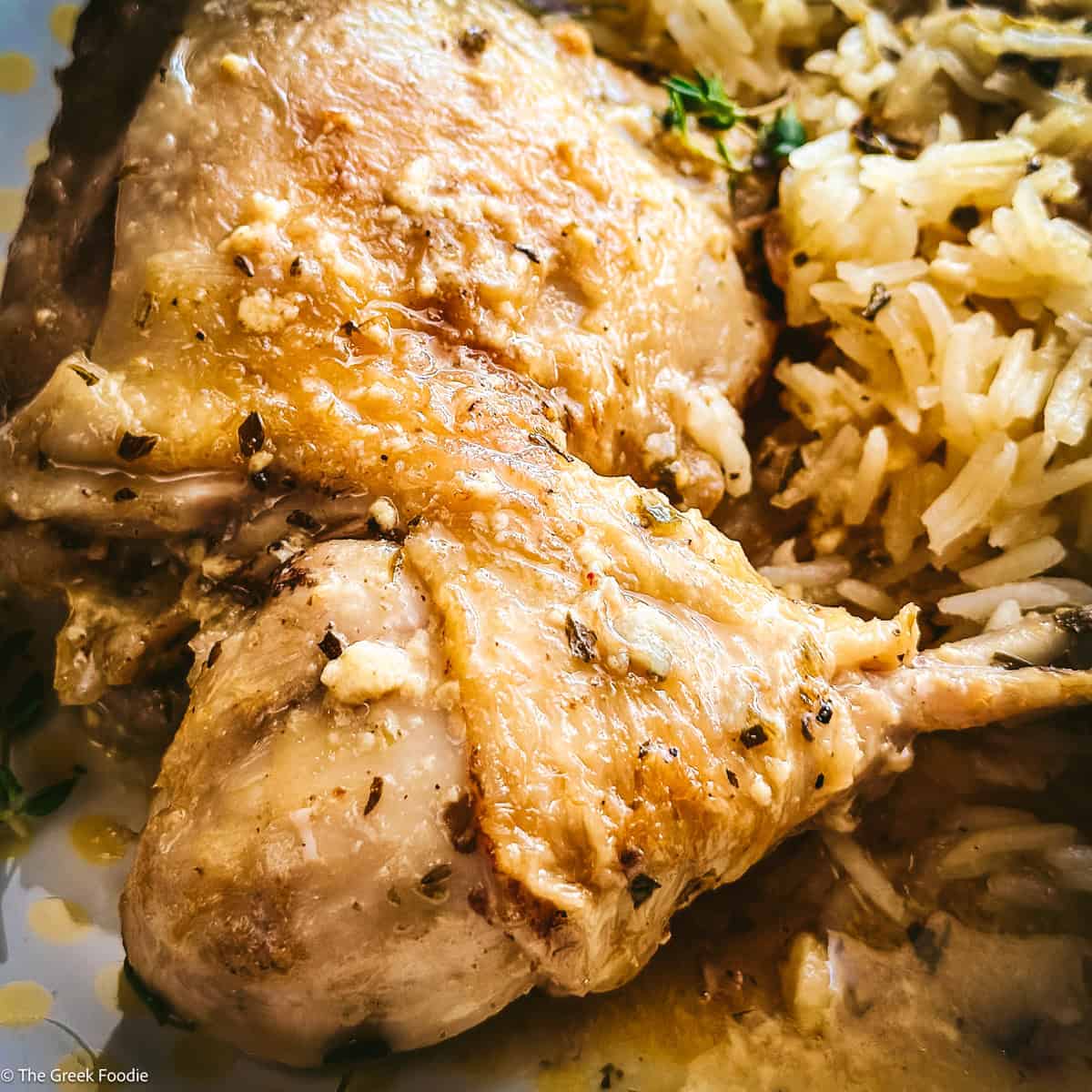 Two pieces of kotópoulo lemonáto — chicken thigh and drumstick — resting on pilafi rice with golden lemon sauce