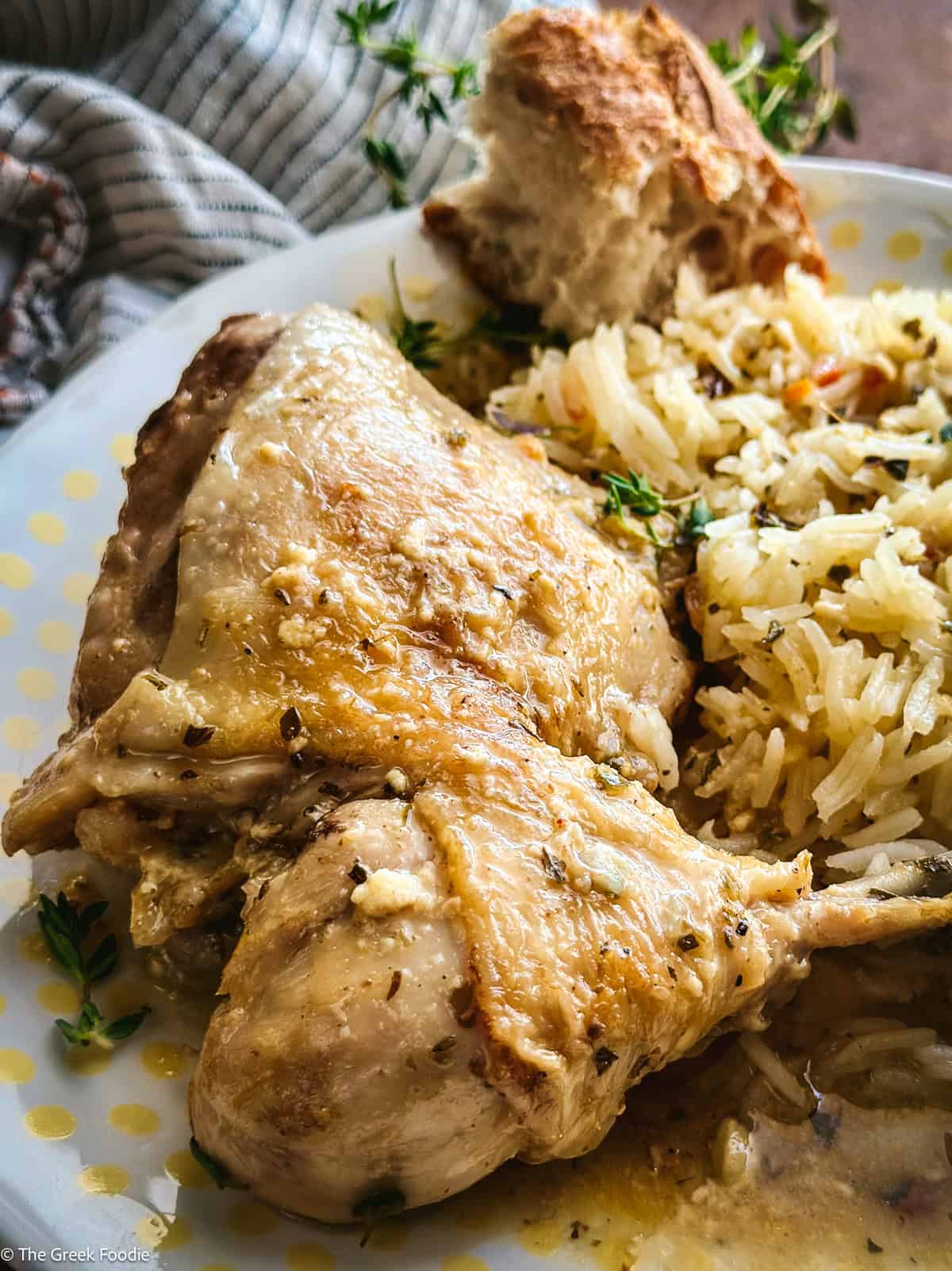 Close up of braised skin-on chicken thigh and drumstick glazed in golden lemon sauce, served on a white plate