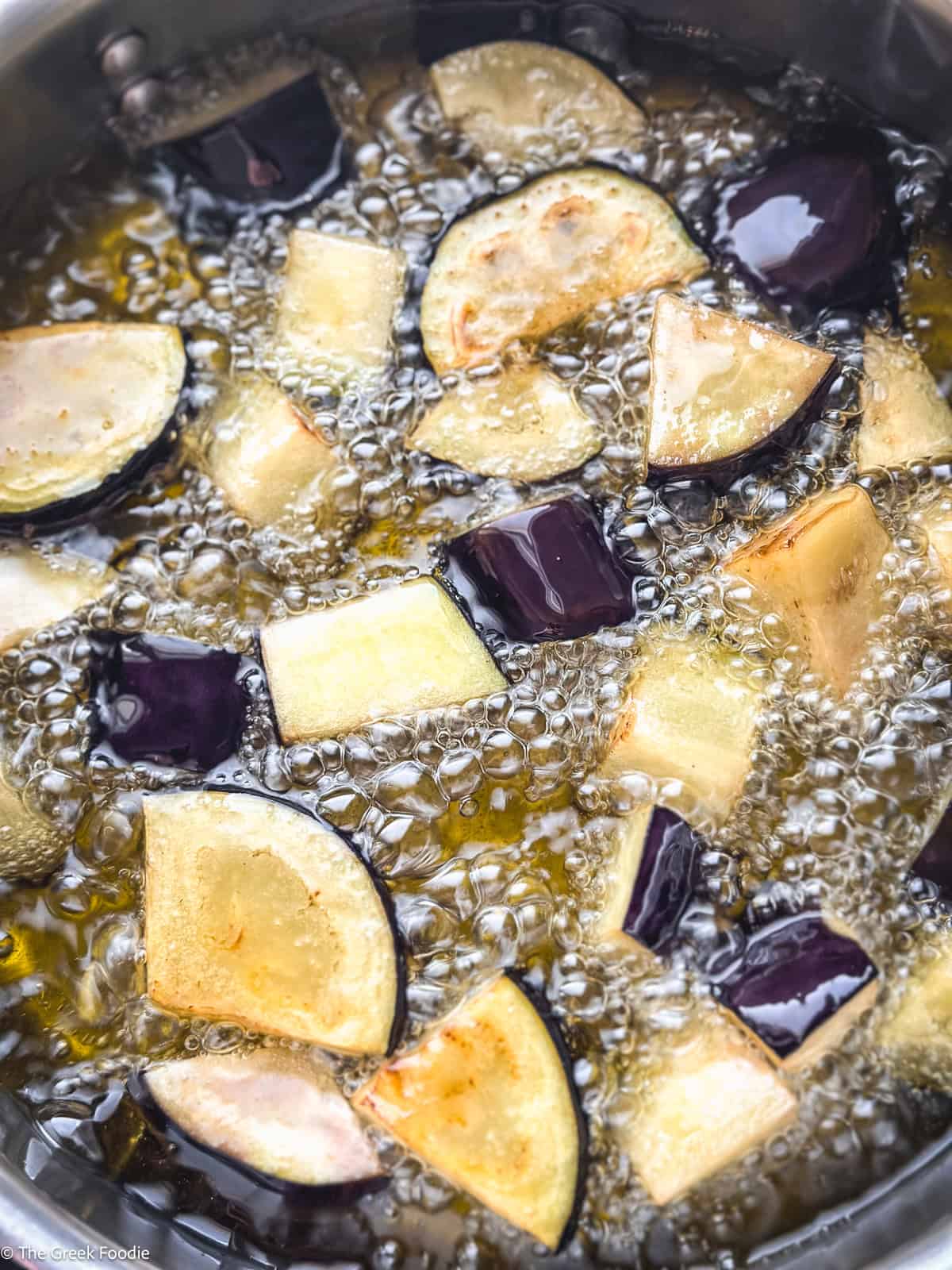 Chunks of eggplant frying in olive oil until golden — part of the spetzofai preparation