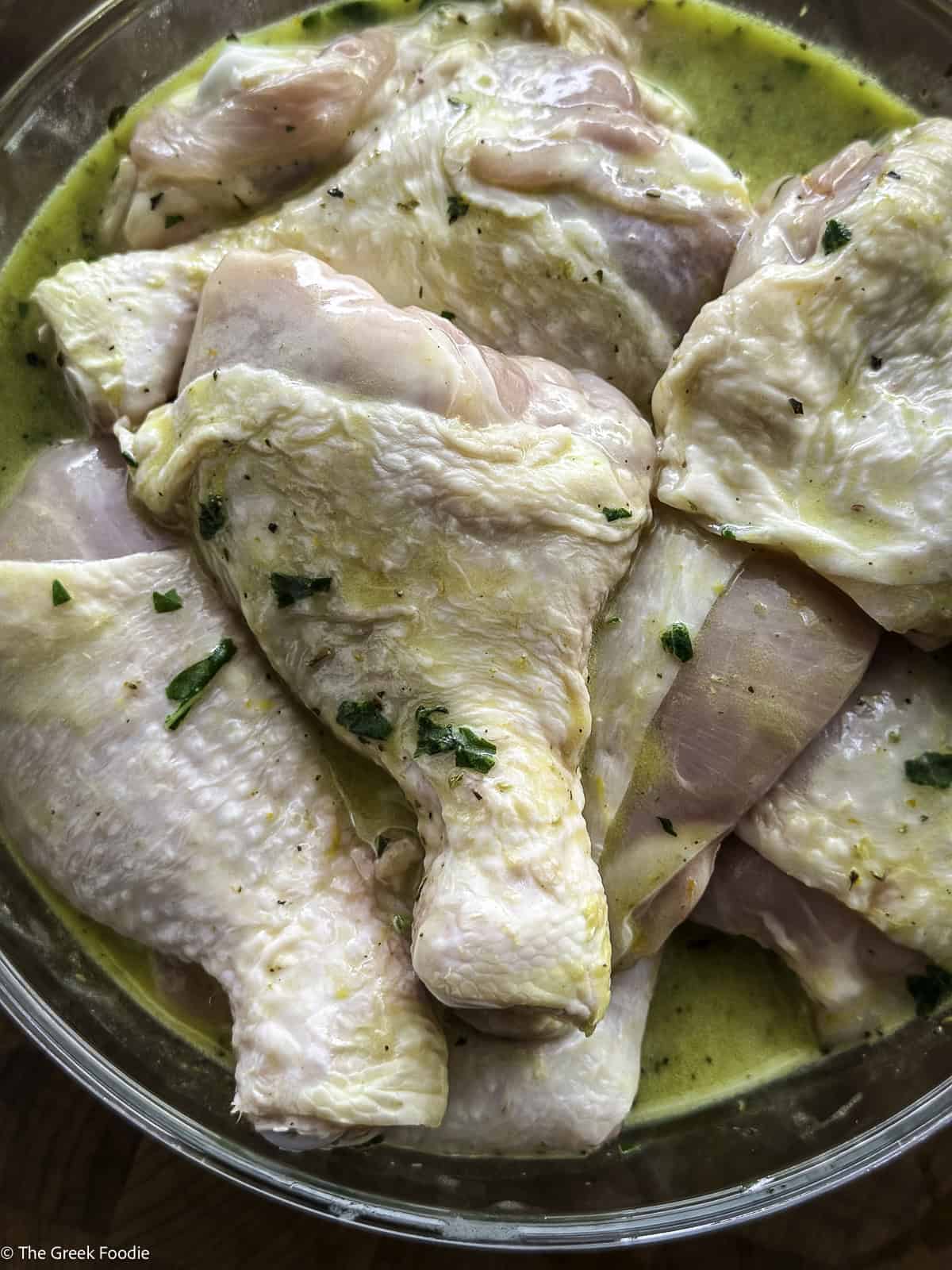 Chicken pieces in a bowl marinating.