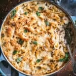 A pan of baked Greek mac and cheese fresh from the oven, with a golden gratinated graviera crust, shell pasta, chilli flakes, and fresh oregano leaves.