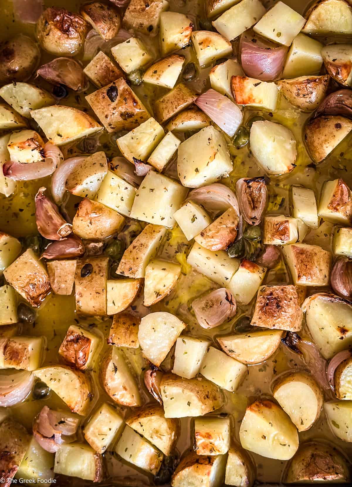 Diced Yukon gold potatoes and red onions on a sheet pan ready to roast